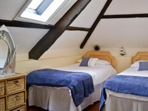 two beds in a attic room with windows at Fordbrook Cottage in Brixton