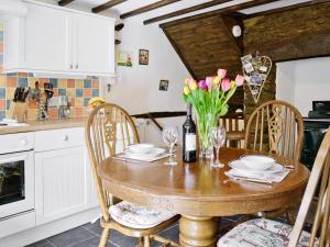 una cocina con una mesa de madera con flores. en Fordbrook Cottage, en Brixton