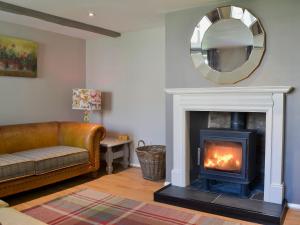 a living room with a fireplace and a mirror at Lowther Cottage in Clifton