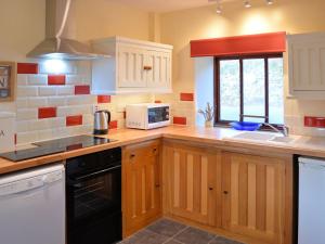 a kitchen with wooden cabinets and a microwave at 3 Benar in Penmachno