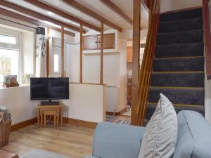 uma sala de estar com um sofá e uma televisão e uma escada em The Cottage em Cross Hands