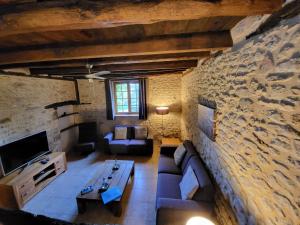 a living room with a couch and a stone wall at Domaine des Grands Bois Privatisé in Sergeac