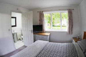 Great Plumstead的住宿－Self contained Stylish 3 Bed Home，一间卧室设有一张床、一个窗口和一台电视