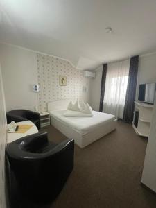 a hotel room with a white bed and a couch at Pension Regal in Satu Mare