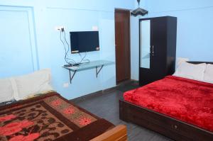 a bedroom with a bed and a desk with a television at AARRAAMS Farms & Resorts in Masinagudi