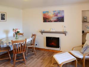 a living room with a table and a fireplace at Eagle Cottage in Culkein