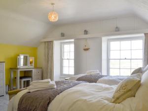 two beds in a room with two windows at Bwthyn Y Borth in Rhoscolyn