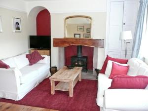 uma sala de estar com dois sofás brancos e uma lareira em Gardeners Cottage em Watermillock