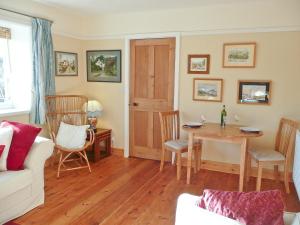 sala de estar con mesa y sofá blanco en Gardeners Cottage en Watermillock