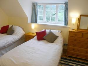 a bedroom with two beds and a window at Gardeners Cottage in Watermillock