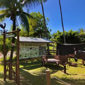 un parque infantil con un cartel, un banco y palmeras en Jardim Atlântico Beach Resort, en Ilhéus