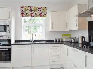 a white kitchen with a sink and a window at The Bungalow in Gatehouse of Fleet