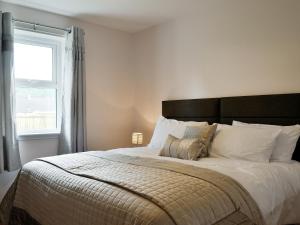 a bedroom with a large bed with a window at The Bungalow in Gatehouse of Fleet