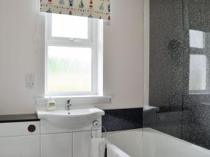 a white bathroom with a sink and a window at The Bungalow in Gatehouse of Fleet