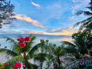 a view of the ocean with palm trees and pink flowers at La Concepcion Cove Garden Resort in Moalboal