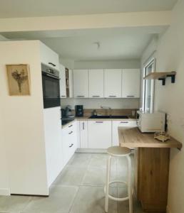 a kitchen with white cabinets and a counter and a stool at Nice 66m with terrace in La Rochelle in La Rochelle