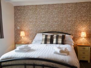 a bedroom with a brick wall and a bed at Yr Hen Feudy in Valley