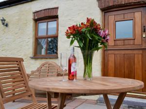 a table with a vase of flowers and a bottle of wine at Yr Hen Feudy in Valley