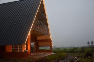 una casa con un techo inclinado con una vaca en un campo en Golden Triangle, en Hampāpura