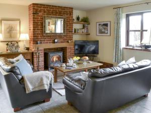 a living room with two leather couches and a fireplace at Riverside Cottage in Costessey