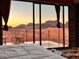 a bed in a room with a view of the desert at Wadi Rum Sky Tours & Camp in Wadi Rum