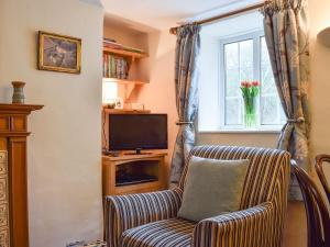 sala de estar con silla y TV en Westover Cottage, en Wootton