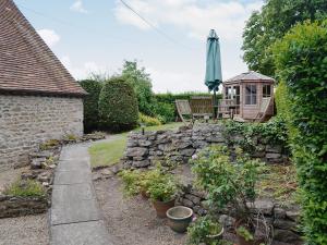 a garden with a stone wall and an umbrella at Westover Cottage in Wootton