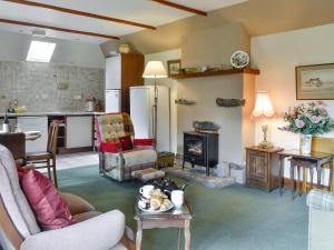 a living room with a fireplace and a kitchen at Rowan Tree Cottage - S4216 in Tulchan