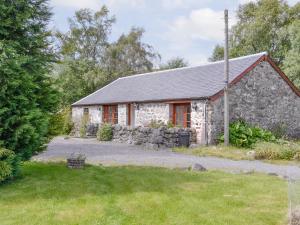 a stone cottage with a gravel driveway in front of it at Rowan Tree Cottage - S4216 in Tulchan