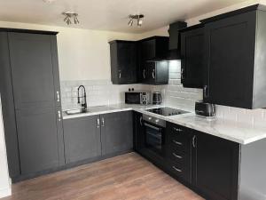 una cocina con armarios negros y encimeras blancas en Stunning Central Apartment With Free Parking, en Sheffield