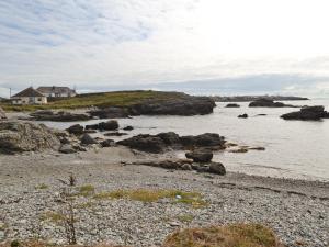 a beach with rocks and a house in the water at Gwelfor in Trearddur