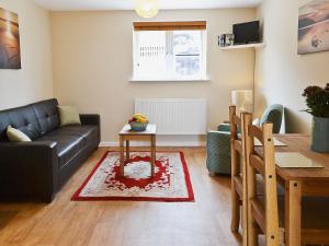 a living room with a couch and a table at The Swallows - 28835 in Royal Wootton Bassett