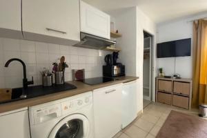 uma cozinha com uma máquina de lavar roupa e um lavatório em Quiet apartment with balcony near the sea em Ouistreham