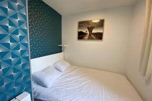 una piccola camera con letto e una foto appesa al muro di Quiet apartment with balcony near the sea a Ouistreham