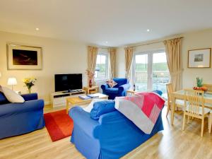 a living room with a blue couch and a tv at Barn Owl Cottage - 27941 in Cambusbarron