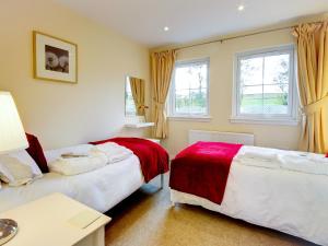 two beds in a room with two windows at Barn Owl Cottage - 27941 in Cambusbarron