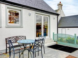 une terrasse avec deux chaises et une table en face d'une maison dans l'établissement Barn Owl Cottage - 27941, à Cambusbarron