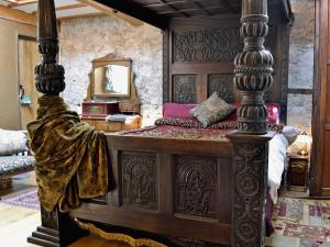Schlafzimmer mit einem großen Holzbett und einem Spiegel in der Unterkunft Hen Wrych Hall Tower in Abergele