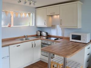 a kitchen with white cabinets and a wooden counter top at High Tide - 30259 in Cromer