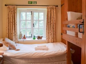 een bed in een kamer met een raam bij Quarrymans Cottage in Linkinhorne