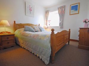 a bedroom with a wooden bed and a window at Robins Nest in Trevilley