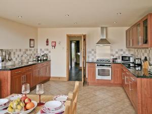 una cocina con armarios de madera y una mesa con un bol de fruta en The Granary - E5483, en Froghall