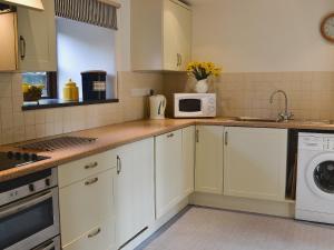 a kitchen with white cabinets and a microwave at Stable End in Trewen