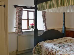 a bedroom with a four poster bed and a window at Stable End in Trewen