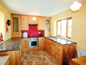 a kitchen with wooden cabinets and a red wall at The Old Dairy - E5394 in Whitchurch Canonicorum