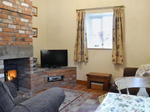 a living room with a fireplace and a television at The Stable - Ijx in Brigham