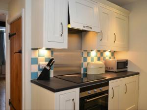 a kitchen with white cabinets and a microwave at Old Town Cottage in Keswick