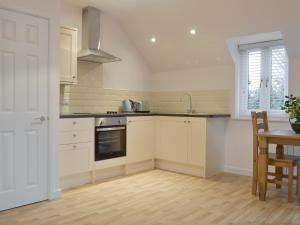 a kitchen with white cabinets and a sink and a table at Hollys Barn in Brent Knoll