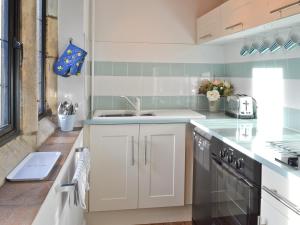 una cocina con armarios blancos y fregadero en The Cottage, en Stroud