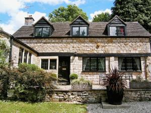 una antigua casa de piedra con una pared de piedra en The Cottage, en Stroud